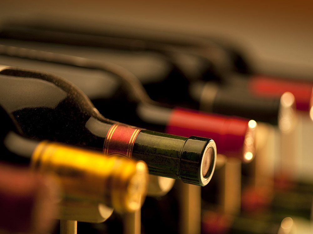 A row of wine bottles from Willamette Valley wineries stored horizontally on a rack.