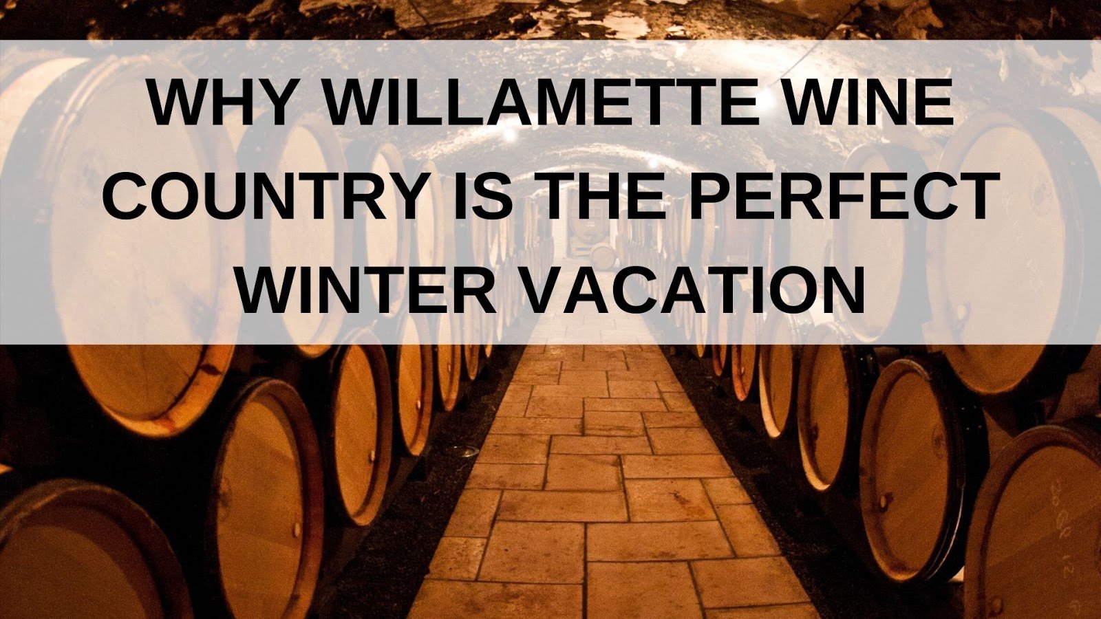 A stone-floored cellar lined with rows of wooden wine barrels, overlaid with the text: “Why Willamette Wine Country is the Perfect Winter Vacation.”